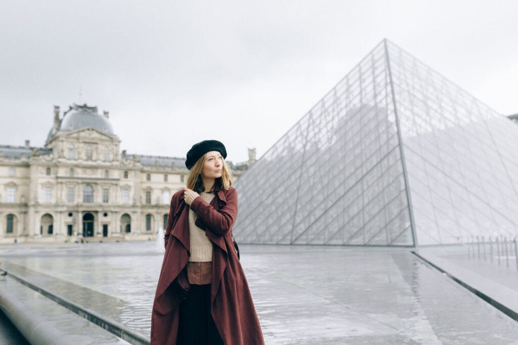 European woman standing by pyramid shaped fountain.