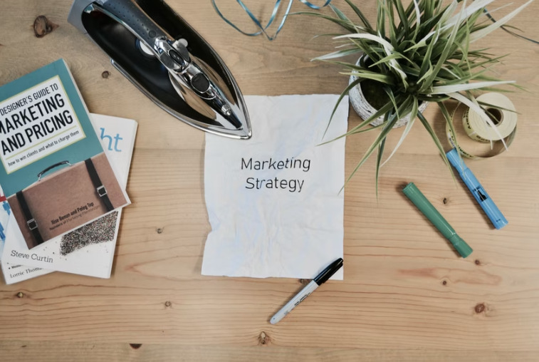 Marketing book, iron, and sharpies on a table.